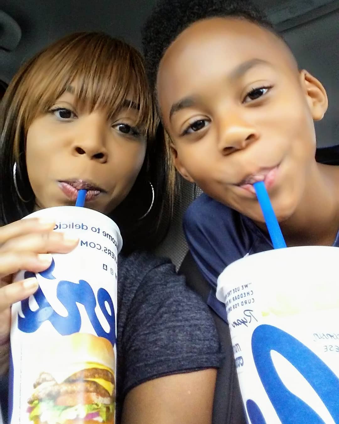 Woman and a young boy drinking from Culver's cups in their car